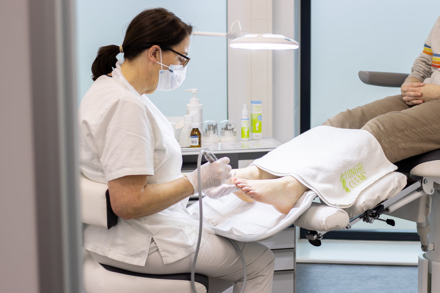Foot care professional performing a foot treatment on a patient with toenail fungus in a clinic.The foot care professional is using FunghiClear to fight toenail fungus.